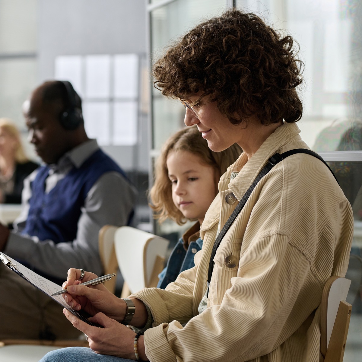 Mother and daughter filling application forms while waiting in line