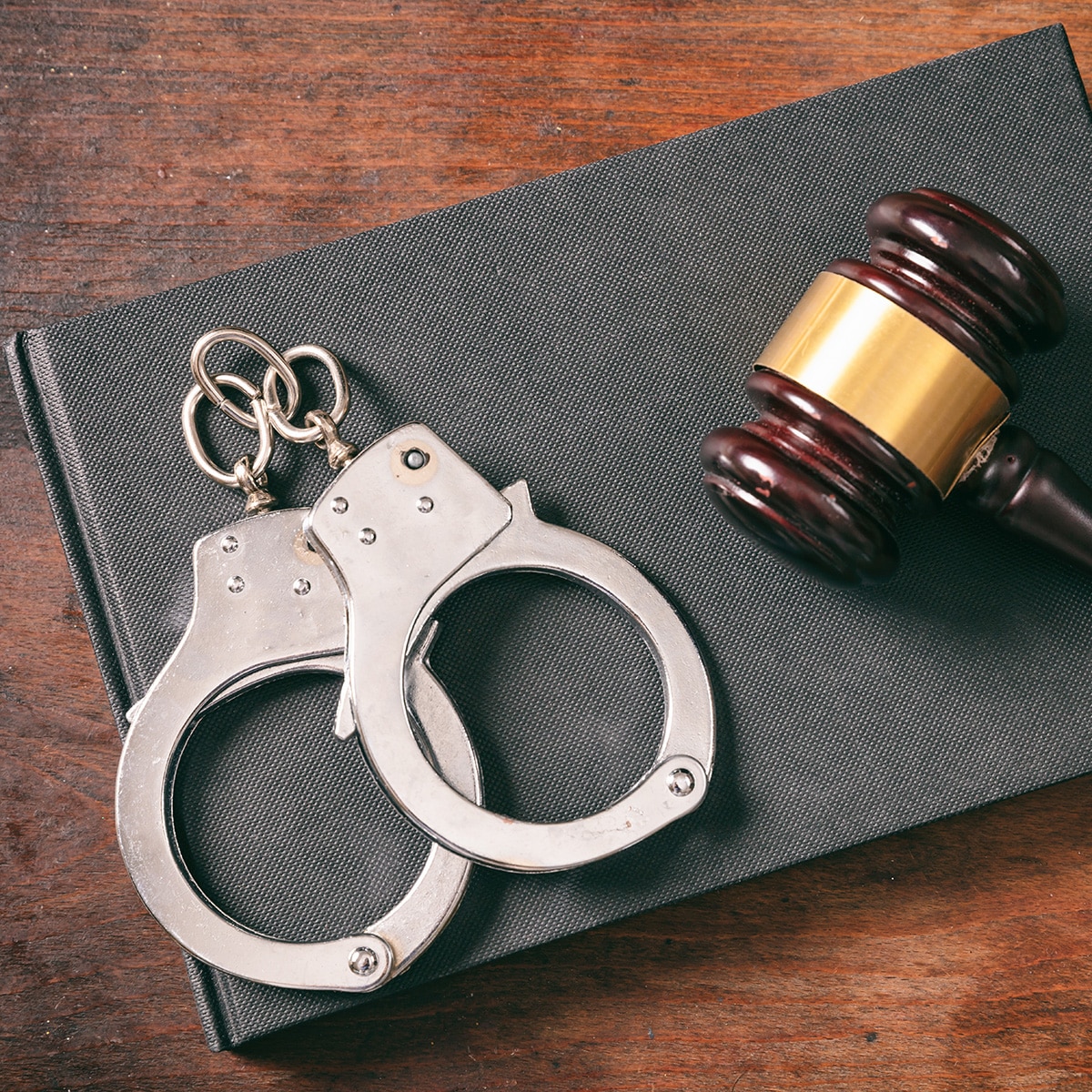 Handcuffs, gavel on book on a wooden background.